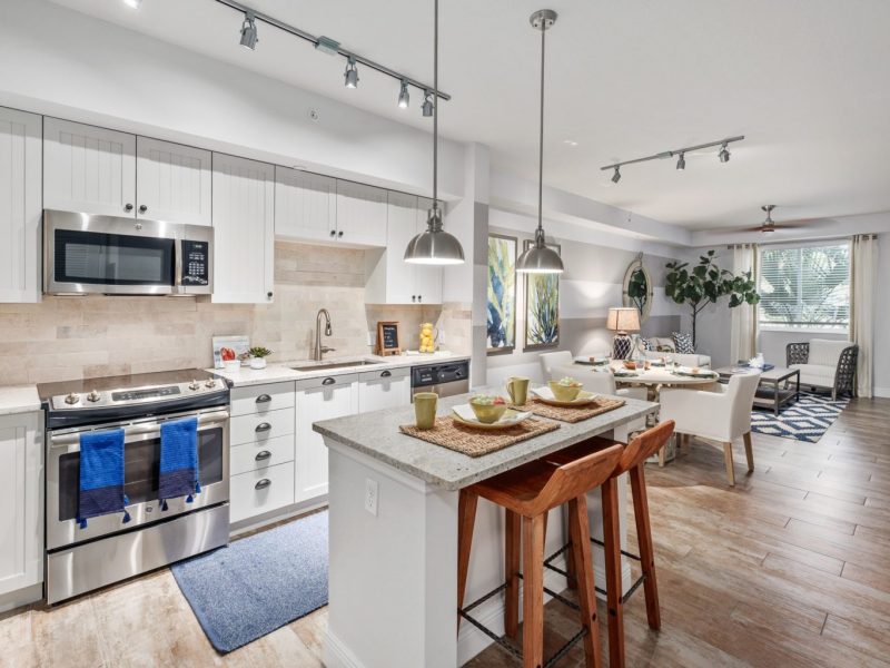 This image shows an expansive view of the kitchen island showcasing accessible kitchen pieces of equipment, and an aisle directly through the dining area.